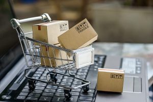 image of shipping boxes in miniature shopping cart on laptop