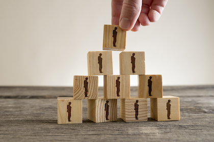 Man stacking a tower of wood blocks with human silhouettes