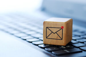 An envelope symbol on a wooden cube on a computer keyboard, with a blurred background and shallow depth of field