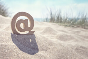 Email @ symbol in the sand at the beach