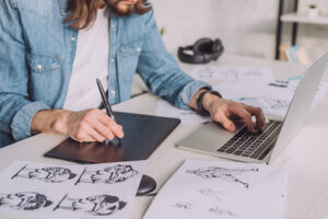 cropped view of animator using gadgets near sketches